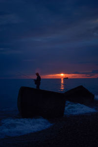 Silhouette man on beach against sky during sunset