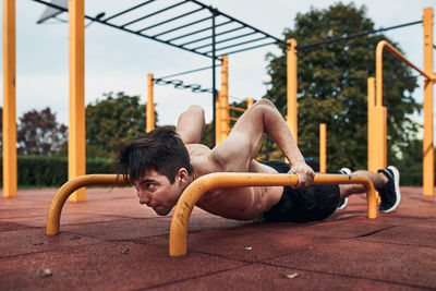 Full length of shirtless man exercising at park