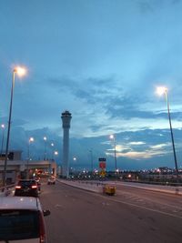 Cars on illuminated street against sky at dusk