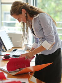 Side view of young woman using laptop while sitting at table