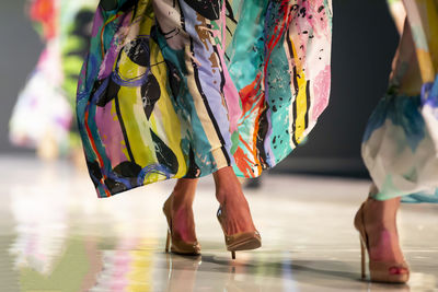 Low section of women standing on multi colored umbrella