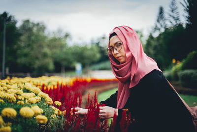 Portrait of woman with red flowers against blurred background