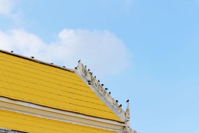 Low angle view of yellow building against blue sky