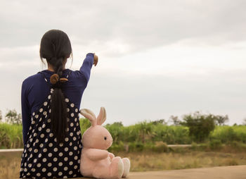 Rear view of woman with arms raised against sky