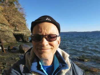 Close-up portrait of senior man on shore against clear sky