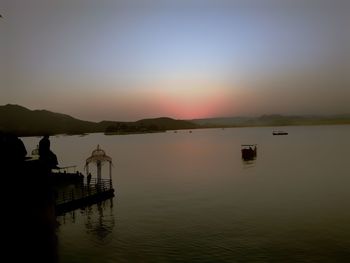 Pier on lake against sky during sunset