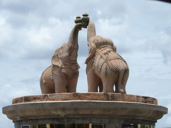 Low angle view of sculpture against cloudy sky