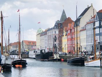 Sailboats in river by buildings in city against sky
