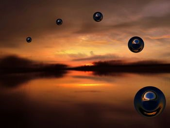 Digital composite image of bubbles over lake against cloudy sky during sunset