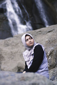 Portrait of woman sitting on rock