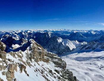 Scenic view of snowcapped mountains against blue sky