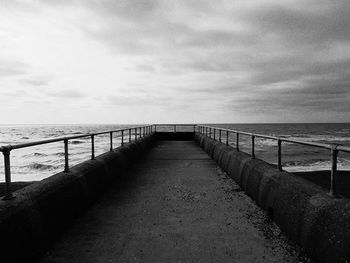 Pier on sea against cloudy sky