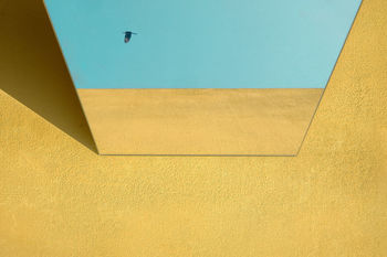 Low angle view of mirror on yellow wall 