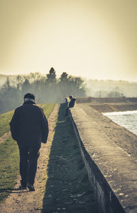 Rear view of men walking on road against sky