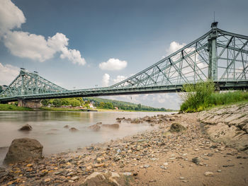 Suspension bridge over river against sky