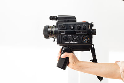 Cropped hand holding camera against white background