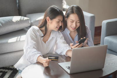 Young woman using mobile phone while sitting on sofa