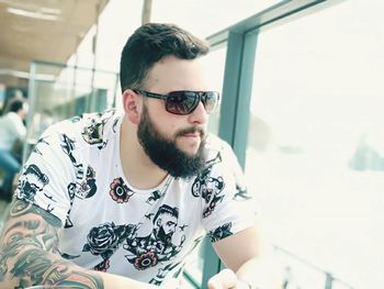 Mid adult man wearing sunglasses while sitting by window