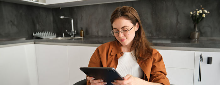 Young woman using digital tablet while standing in office