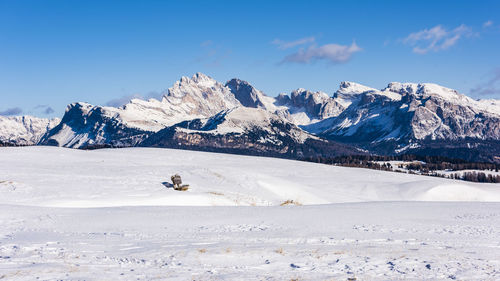 Scenic view of snow covered mountains against blue sky