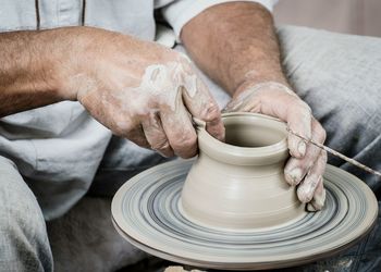 Midsection of man making clay pots