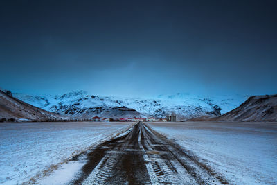 Road amidst snowcapped mountains against sky