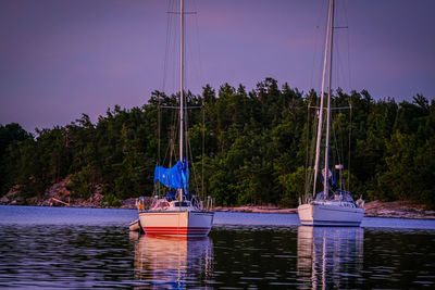 Sailboats moored on lake against sky