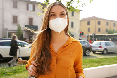 Young woman wearing mask looking away outdoors