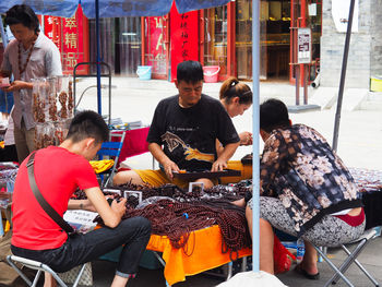 People sitting at market stall in city