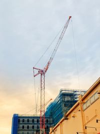 Low angle view of cranes at construction site against sky