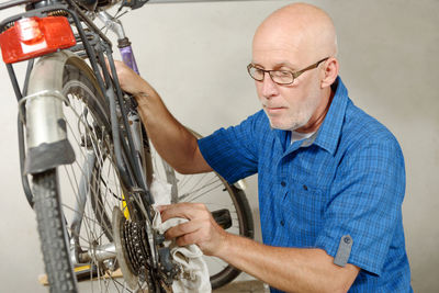 Mature man cleaning bicycle in garage