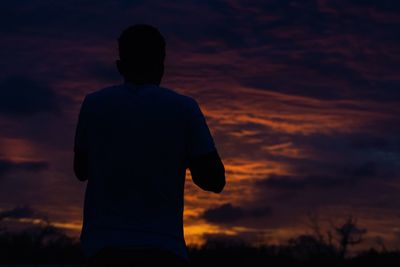 Rear view of silhouette man standing against sky during sunset