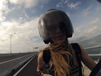 Woman wearing helmet while riding motorcycle on against sky