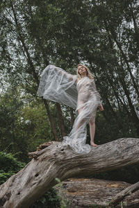 Woman standing by tree in forest