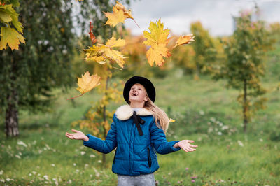 Portrait of smiling young woman standing against trees