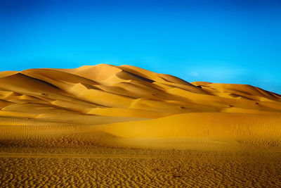 Scenic view of desert against clear blue sky