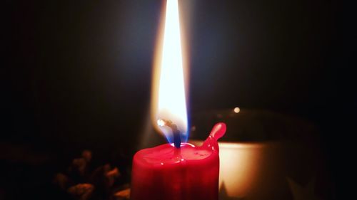 Close-up of lit candle in darkroom