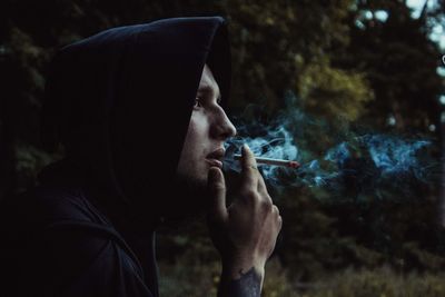 Side view of man smoking cigarette outdoors