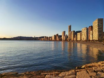 Sea by buildings against clear blue sky