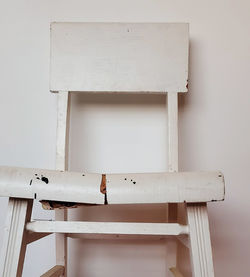 Close-up of empty chair on table against wall