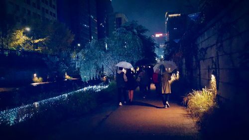 People walking on illuminated street at night