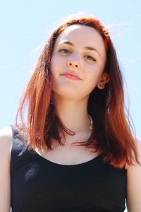 Low angle portrait of redhead woman against sky