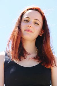 Close-up portrait of smiling young woman against sky