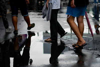 Low section of people walking on wet road