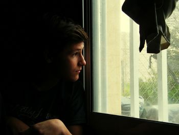 Close-up portrait of a young woman looking through window