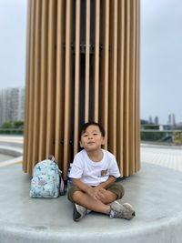 Cute asian boy sitting on chair in playground 