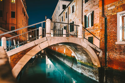 Arch bridge over canal in city at night