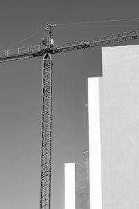 Low angle view of crane at construction site against sky