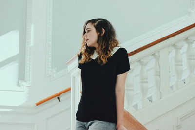 Low angle view of young woman standing on staircase at home