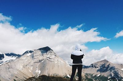 Low angle view of woman standing on mountain against cloudy sky